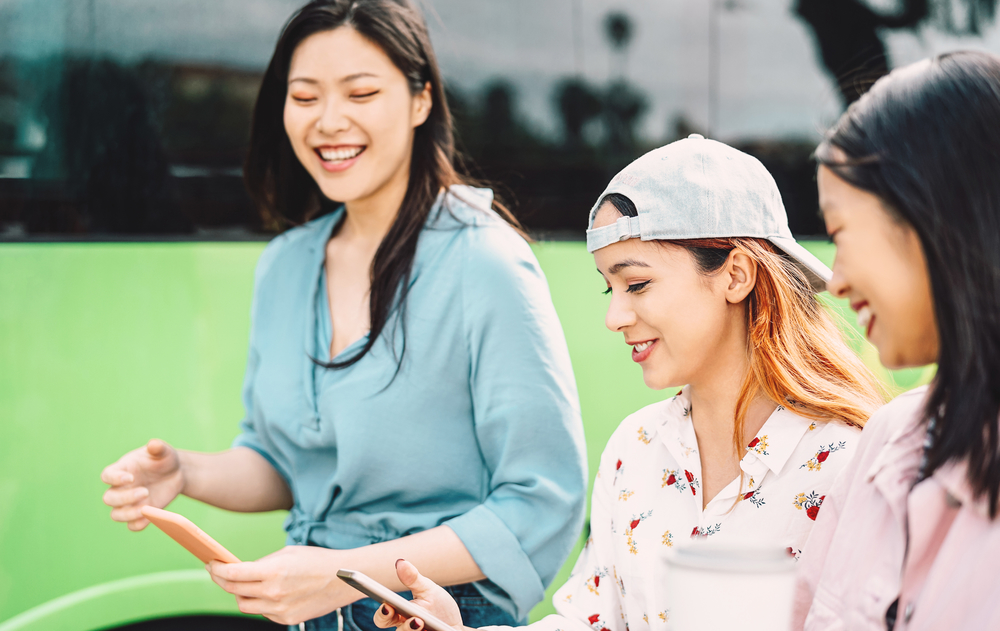 Happy Asian girls using mobile phone outdoor – Young millennial
