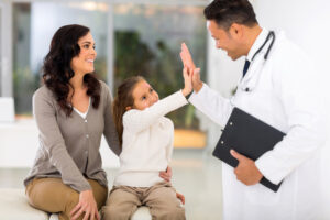 happy little girl and pediatrician doing high five after medical checkup