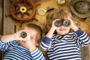 Happy kids playing with nautical things. Children having fun at home. Travel and adventure concept. Unusual high angle view portrait